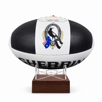 A black and white rugby ball with the Collingwood Football Club logo, displayed on a clear stand with a dark brown wooden base against a white background.