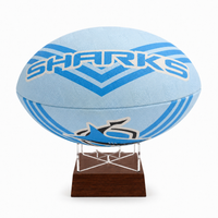 A light blue and blue striped rugby ball with 'SHARKS' printed in white and blue, displayed on a clear acrylic stand with a dark brown wooden base against a white background.