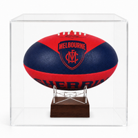 A red and navy blue Melbourne Demons Football Club AFL ball urn displayed on a clear acrylic stand inside a transparent display case, set against a plain white background.