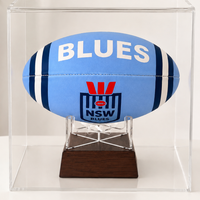 A light blue NSW Blues rugby ball displayed inside a clear acrylic case on a dark wood stand, set against a clean white background.