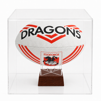 A white St George's Dragons rugby ball urn displayed inside a clear acrylic display case on a dark wood stand.