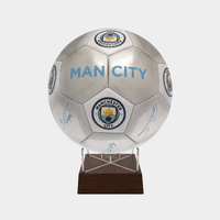 A Manchester City soccer ball signed by players, mounted on a clear acrylic stand with a dark brown wooden base, shown against a light gray background.