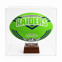 A bright green Canberra Raiders rugby ball displayed inside a clear acrylic cube case on a dark wooden stand, photographed against a plain white background.