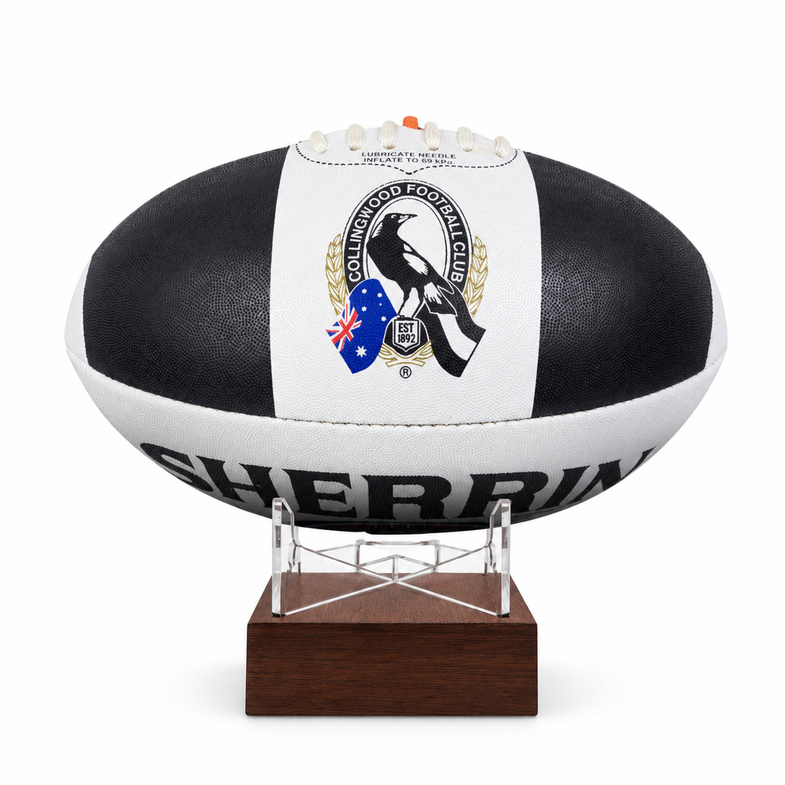 A black and white rugby ball with the Collingwood Football Club logo, displayed on a clear stand with a dark brown wooden base against a white background.