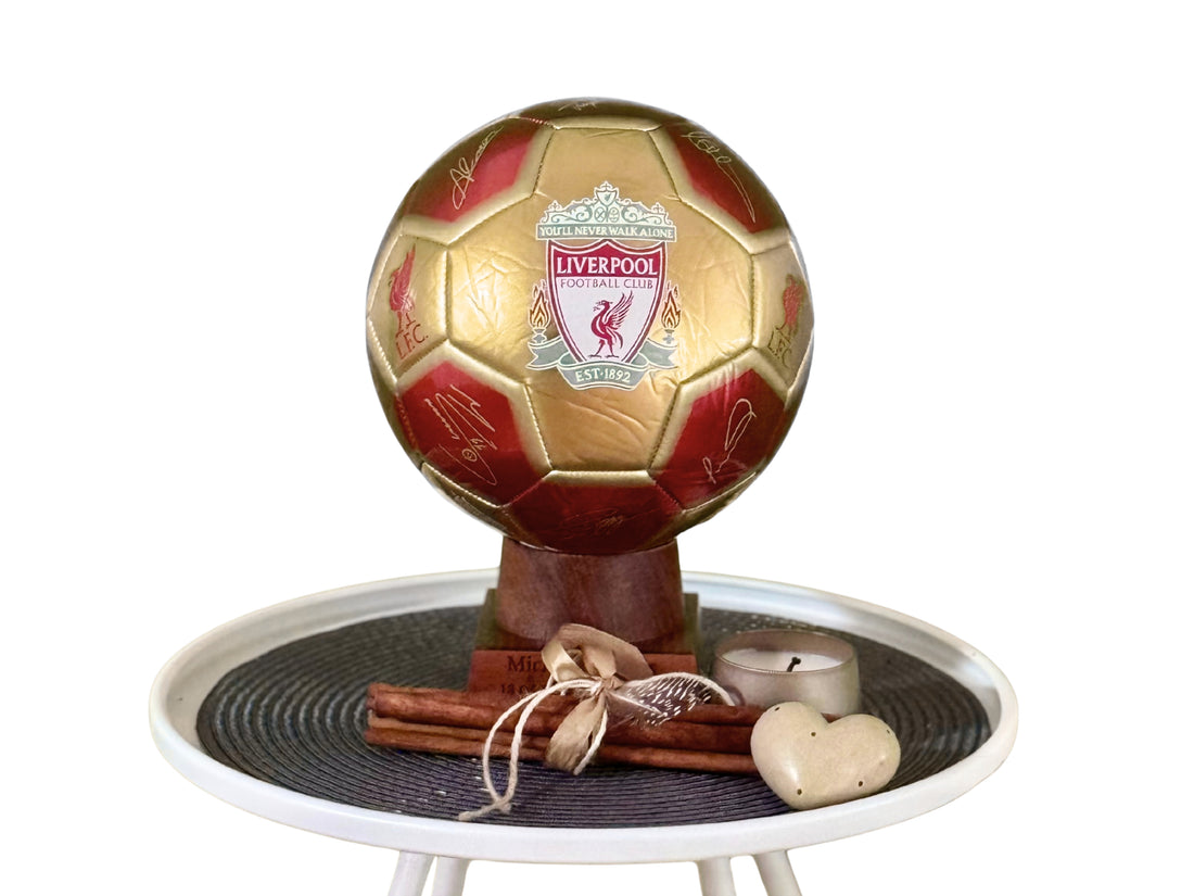 Gold and red soccer ball with Liverpool FC logo on a decorative stand.