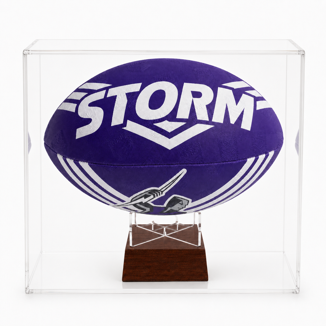 A purple and white Storm NRL jersey rugby ball mounted inside a clear acrylic display case on a dark wood stand, photographed against a white background.