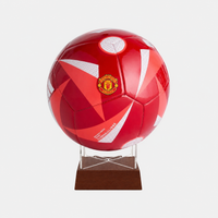 A red and white Manchester United soccer ball mounted on a clear acrylic stand with a dark brown wooden base, set against a light gray background.